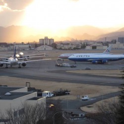 A United Boeing 747-400 and American Airlines Boeing 777 sit while other aircraft start to line up.