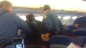 Looks like the unruly passenger got his shirt back on in time for the police to escort him off the plane.