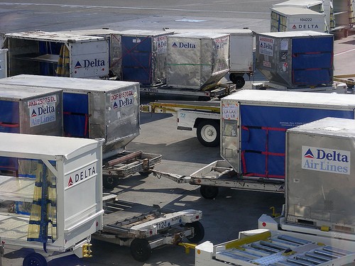 Can you find the three generations of Delta Air Line logos on the baggage carts?