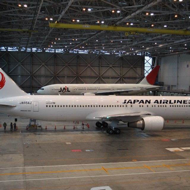 A Boeing 777-200 (JA0090) sits in the hangar with the Boeing 767 (JA654J)