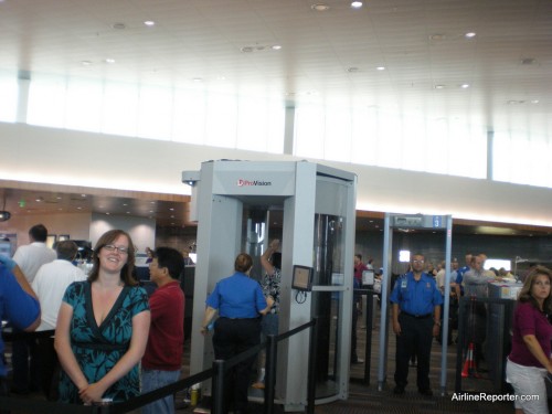 That's Amy smiling. You can see another woman being scanned. The TSA agent who yelled at me is stating in the metal detector.