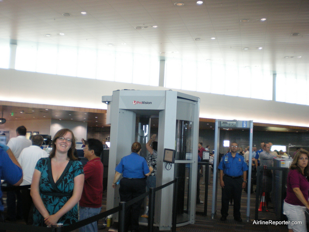 That's Amy smiling. You can see another woman being scanned. The TSA agent who yelled at me is stating in the metal detector.