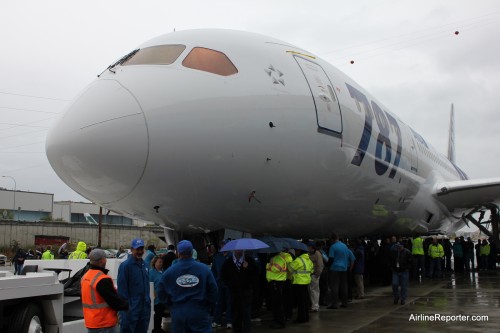 Boeing employees huddle under the 787 Dreamliner to get out of the rain.