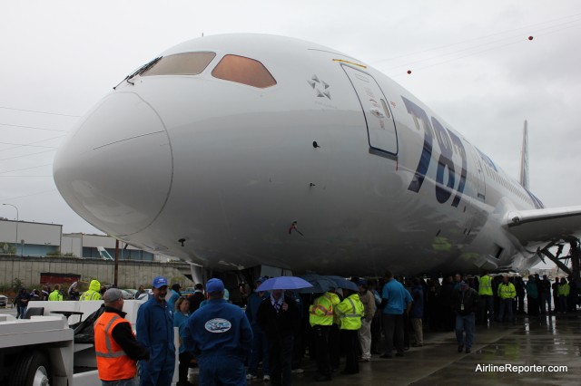 Boeing employees huddle under the 787 Dreamliner to get out of the rain. 
