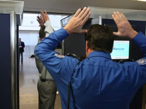 A Transportation Security Administration employee demonstrates a backscatter X-ray body scanner, following the directions of a screener, at Sea-Tac Airport.