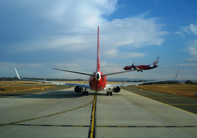 A QANTAS 737-800 awaits take-off clearance as Virgin 737NG lands. Photo by Owen Zupp.