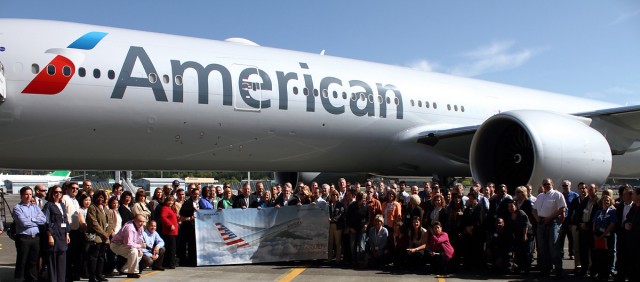 Employees of American stand around a Boeing 777-300ER in new AA livery. 