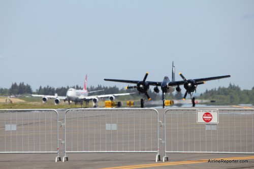 A Grumman F7F Tigercat, called Bad Kitty, returns from a flight, as a Cargolux Boeing 747-8F spools up for take off. You have to love Paine Field.