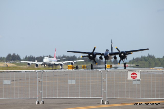 A Grumman F7F Tigercat, called Bad Kitty, returns from a flight, as a Cargolux Boeing 747-8F spools up for take off. You have to love Paine Field. 