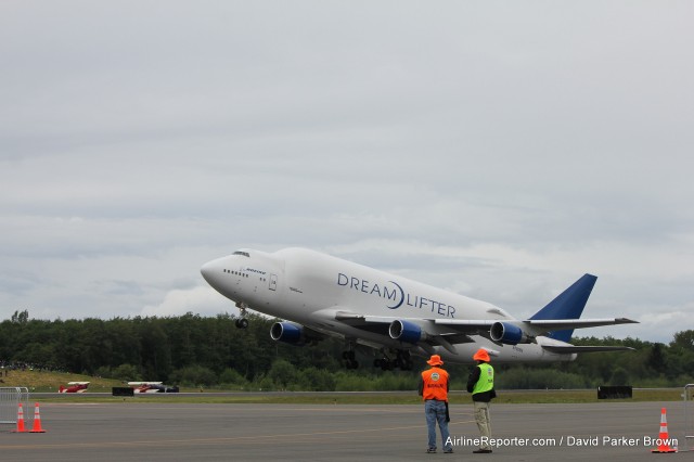 A Boeing 747 Dreamlifter lifts off as volunteers watch. Notice the classic bi-planes (which guests could pay to fly on) in the background. 