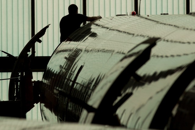 A worker polishes a fuselage on an airplane.