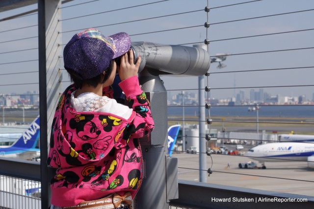 An AvGeek-in-training uses a telescope on HND T2's observation deck. See the cables?