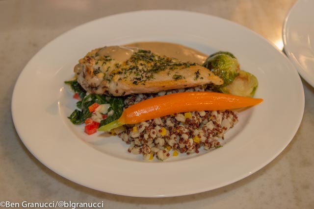 Chicken served over a quinoa salad with carrot and brussels sprouts.
