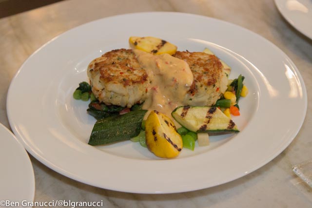 Crab cakes over succotash with mixed fresh vegetables.