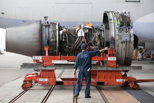 A mechanic directs the location of an engine.