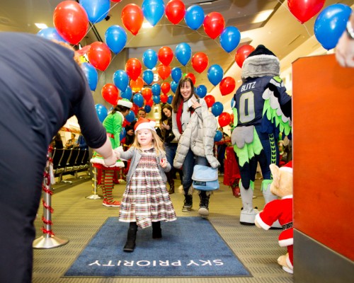 The first child to board turns in her ticket to the gate agent to board the jet.