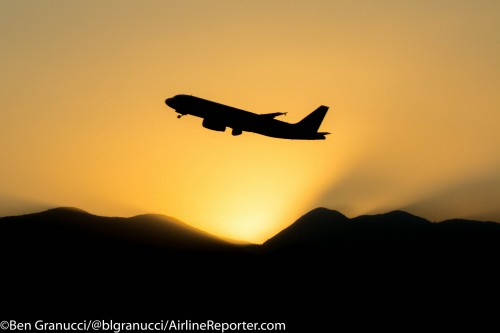 A magnificent view of a departure as the sun sets behind the mountains. Shot inside the lounge.