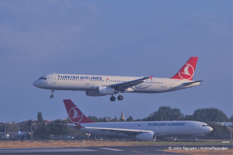 A Turkish Airlines A321 (TC-JRT) landing at IST, with a Turkish Cargo A330 parked in the background.