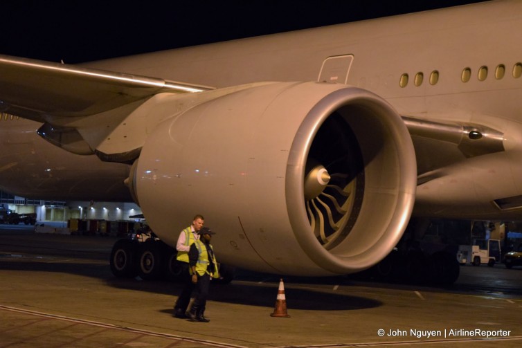 Ground crew stand next to a American Airlines 777-300ER's huge GE90 engine.