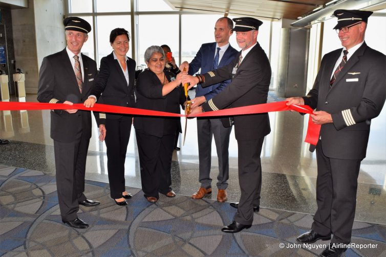 The inaugural 777-300ER flight crew helps cut the ribbon before departure.