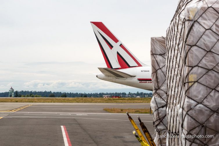 An ABX Air 767-232F taxis past cargo pallets being prepared for loading.