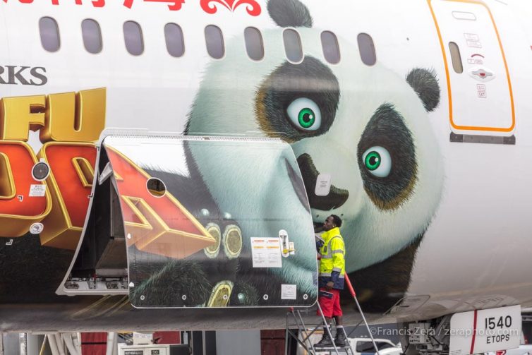 An airport worker opens a cargo door on Hainan Airlines' Kung Fu Panda 787-9 as it arrives on its first visit to the U.S.