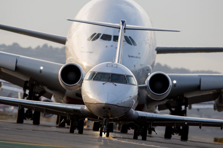 A tiny Bombardier CRJ-200 is shadowed by the looming figure of an Airbus A380 as the two await to depart San Francisco International Airport on October 23, 2016