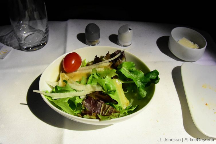 Salad: Seasonal salad with jicama and tomato, presented with dressing.