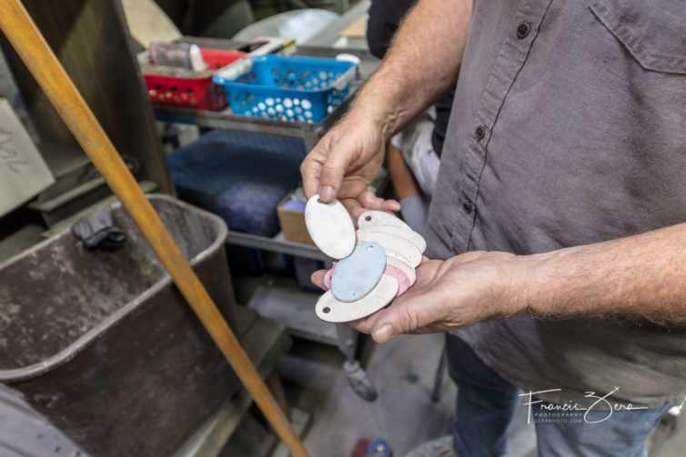 Hall shows off a stack of tags that are in the middle of the manufacturing process.