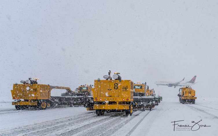 A Delta 737 prepares to land as one of Seattle-Tacoma International Airport's snow-removal teams waits to cross the active runway.