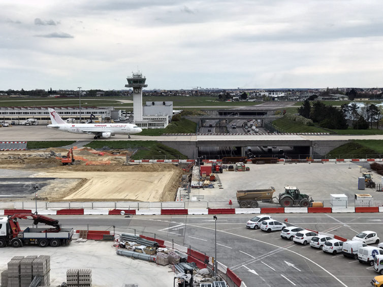 Views from the ORY observation deck encompass a couple of taxiways, an entrance road, and a runway.