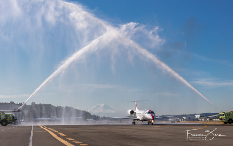A JetSuiteX ERJ135 getting a water cannon salute at Boeing Field - Mount Rainier provided a dramatic backdrop