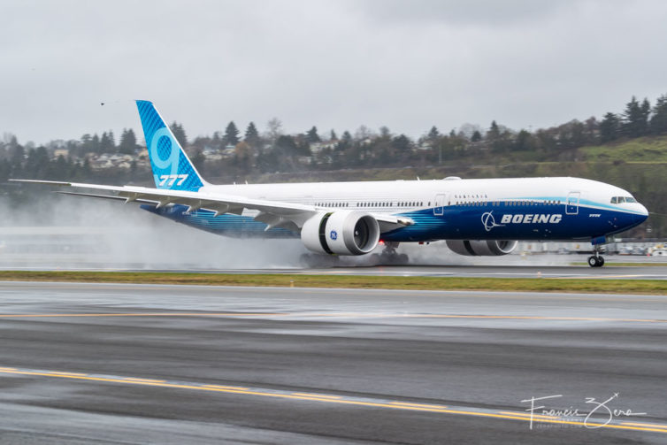The 777X kicks up a big plume of spray as it lands on a wet runway at Boeing Field after its first flight