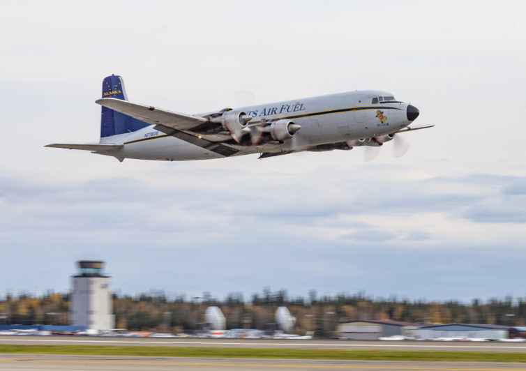 N7780B making a grand departure on 20R. Spotter tip: they climb slowly to build airspeed and loaded fuel tankers depart away from the more populated areas whenever possible. The tower and south end of the east ramp are visible in the background, the pizza place is just out of frame to the left.