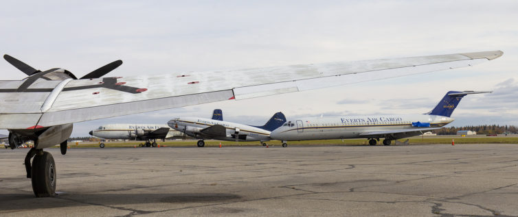 A very nice lineup on the Everts Air ramp, with a DC-6, C-46, and DC-9, framed beneath the wing of another C-46.