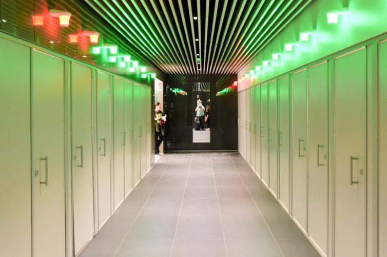 A long hall of doors to private stalls with indicator lights showing if they are occupied.