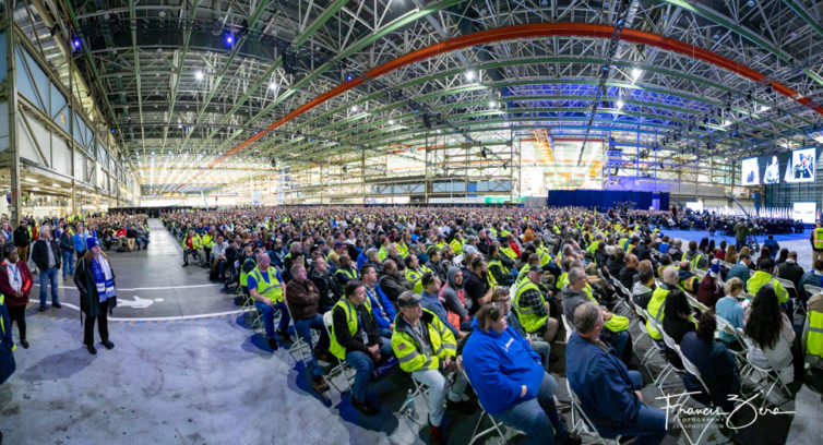 Thousands of Boeing employees, visitors, and guests fill the enormous manufacturing plant that housed the 747 assembly line. 