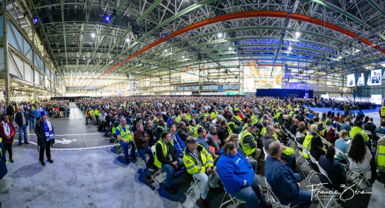 Thousands of Boeing employees, visitors, and guests fill the enormous manufacturing plant that housed the 747 assembly line.