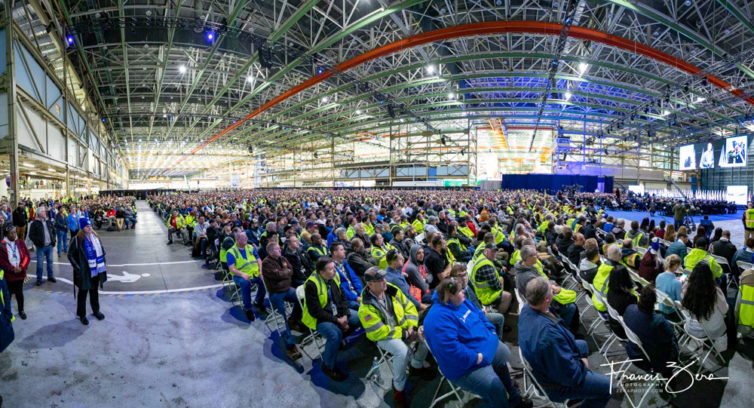 Miles de empleados, visitantes e invitados de Boeing llenan la enorme planta de fabricación que albergaba la línea de montaje del 747. 