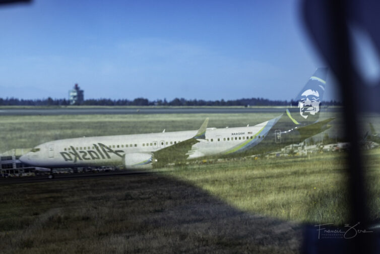 A jetliner reflected in a car window